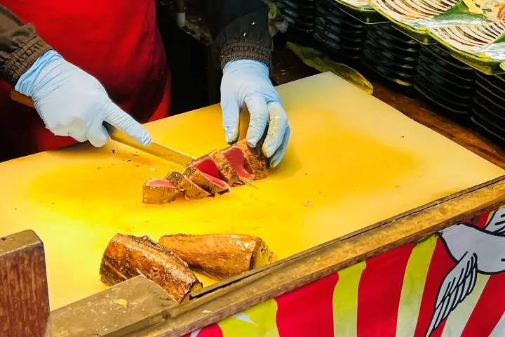 土佐タタキ道場で藁焼きしたカツオを包丁で厚切りにする様子